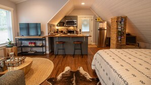 A compact kitchen with a microwave, refrigerator, and wooden bar stools. - Quant carriage House, near the city of Asheville and Ashville Airport! (Arden)