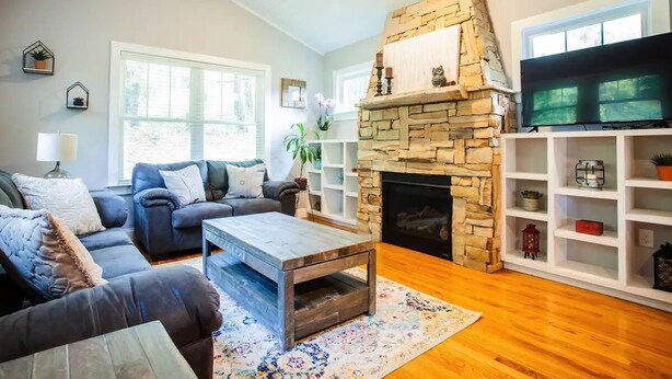 A living room with a stone fireplace, a television, and a bookshelf.