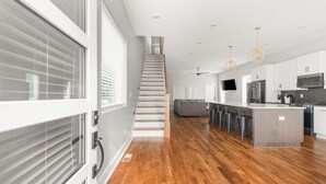 A modern kitchen with wooden flooring, white cabinets, a central island, and a staircase leading to another level. - New home in Nashville built in 2023! Extremely spacious, great for hosting
 (Nashville)