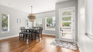 A dining area with a wooden table and chairs, large windows with blinds, and a patterned rug. - New home in Nashville built in 2023! Extremely spacious, great for hosting
 (Nashville)