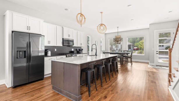 A modern kitchen with white cabinets, a stainless steel refrigerator, a central island with bar stools, and pendant lighting. - New home in Nashville built in 2023! Extremely spacious, great for hosting
 (Nashville)