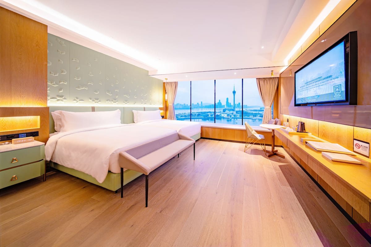 Une chambre d’hôtel moderne, dotée d’un grand lit, d’un bureau et d’une télévision.