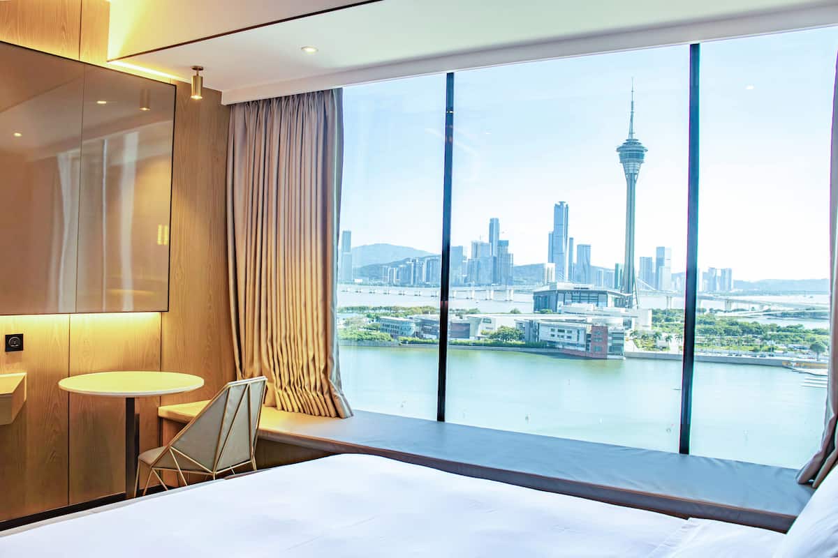 Une chambre d’hôtel dotée d’une grande fenêtre donnant sur le panorama urbain et une tour.