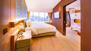 A modern hotel room with a large bed, a bedside table with a lamp, a TV mounted on the wall, and a view of the city through large windows.