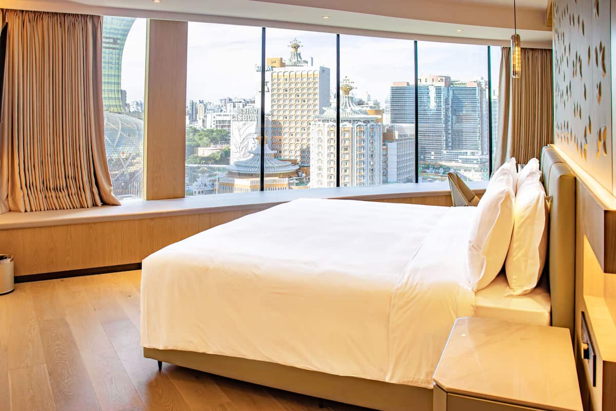 Une chambre d’hôtel avec un grand lit, une vue sur la ville et une fenêtre avec des rideaux.