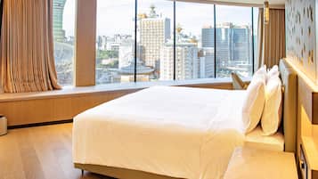 A hotel room with a large bed, a view of the cityscape, and a window with curtains.