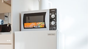 Un refrigerador blanco con un microondas encima, un panel de control y una etiqueta de marca.