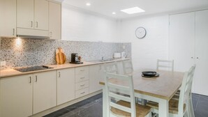 Een moderne keuken met witte kasten, een granieten aanrechtblad en een eethoek met een houten tafel en stoelen.