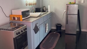 A compact kitchen with a gas stove, microwave, sink, and a refrigerator. - In City - Minutes to Regent St, Botanical Gardens, Cuffy Sq, and Bourda Market.  (Georgetown)