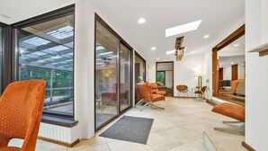 Un vaste espace de vie doté de grandes portes vitrées donnant sur un balcon, de meubles modernes et d’un luminaire encastré au plafond.