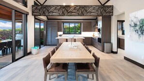 Une cuisine moderne avec des meubles de couleur bois foncé, un îlot central et une grande fenêtre.