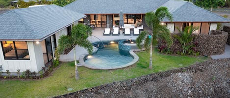 A modern house with a swimming pool, a covered patio, and a view of the ocean.