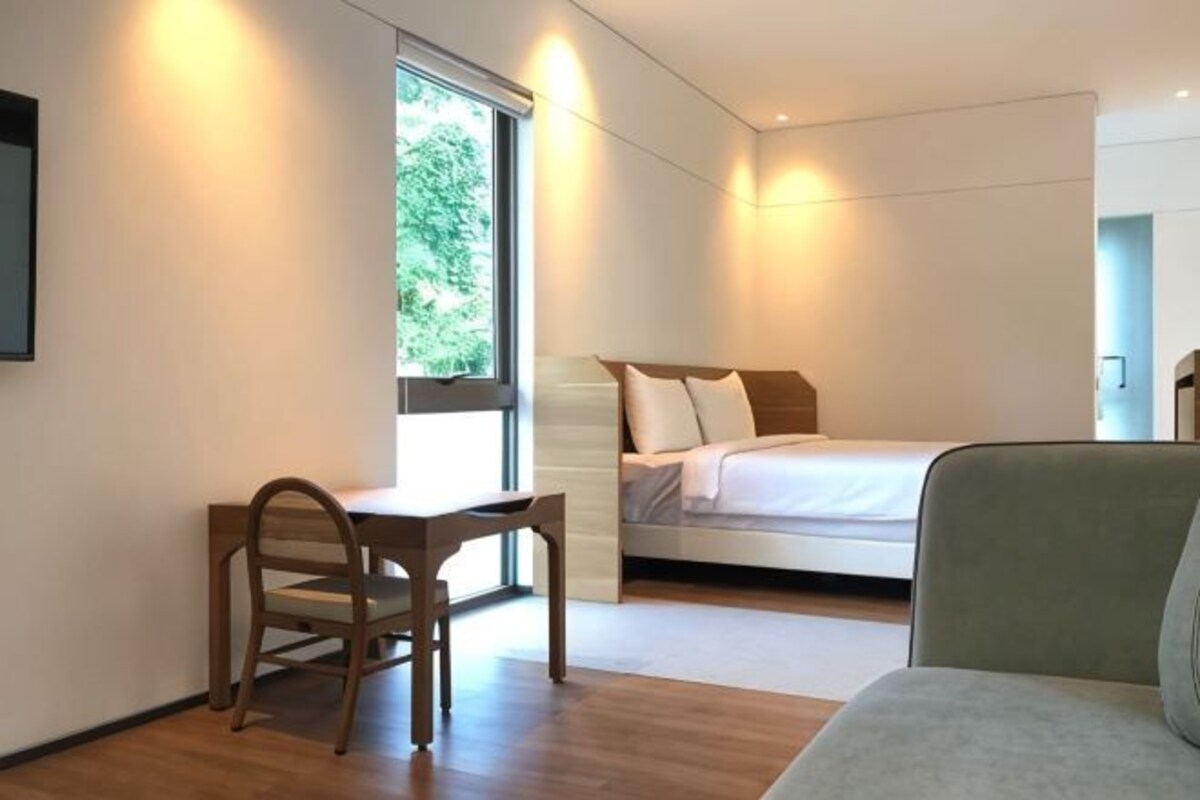 A bedroom with a bed, a desk, and a chair.