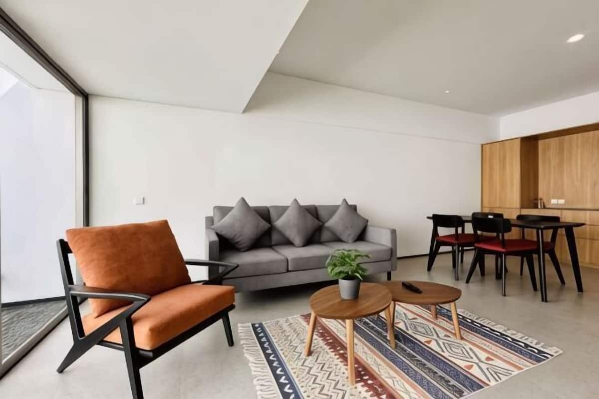 A modern living room with a sofa, armchair, coffee table, and dining area.