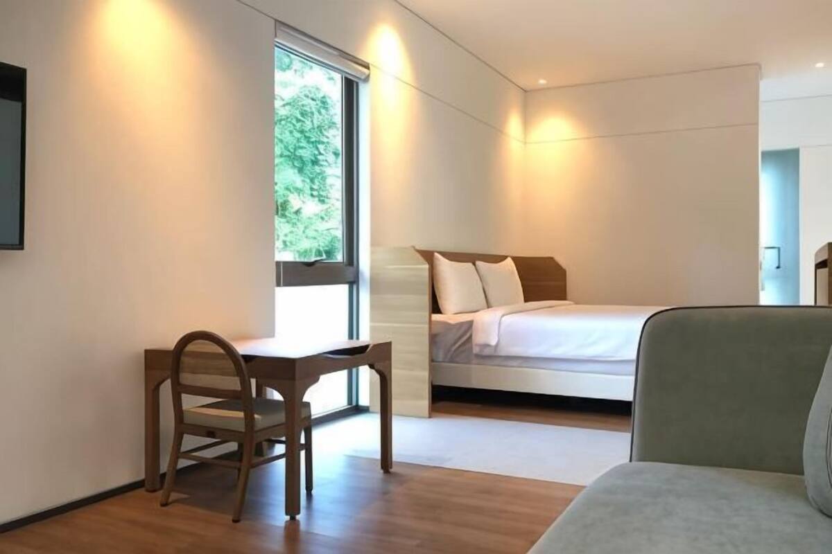 A bedroom with a bed, a desk, and a chair.