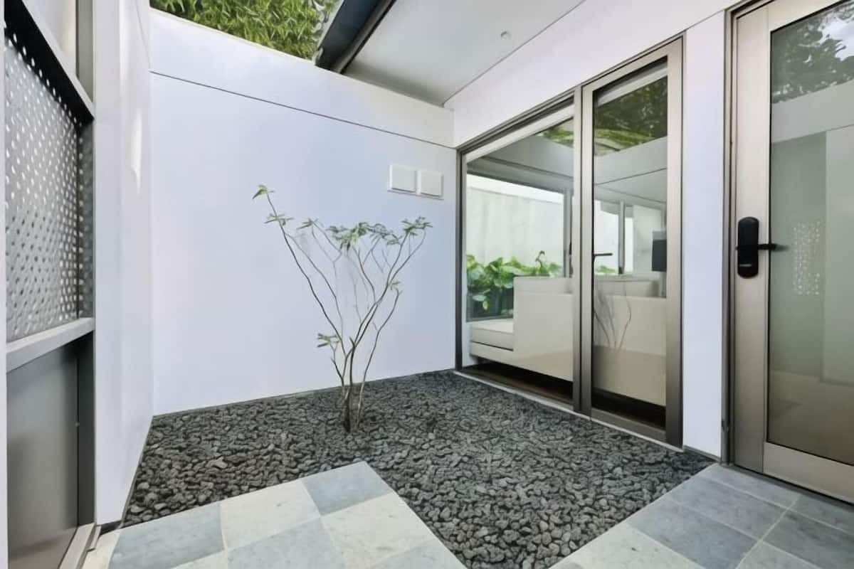 A modern interior with a glass door, a small plant, and a tiled floor.