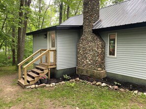 Eine Hütte mit einem Steinkamin, einer Holztreppe und einer kleinen Veranda.