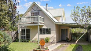 Une maison à deux étages avec un balcon, une véranda à l’avant et une cour clôturée.