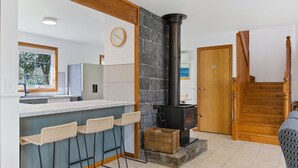 Une cuisine moderne avec une cheminée en pierre, un escalier en bois et une vue sur l’extérieur.