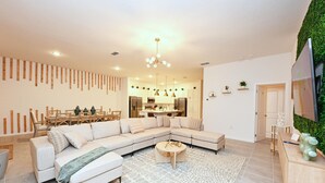 Una sala de estar moderna con un sofá modular, una mesa de centro y un comedor con una mesa y sillas de madera.