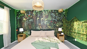 Un dormitorio con un mural de pared con temática de selva en tonos verdes, una cama con una manta verde y dos mesitas de noche con lámparas.