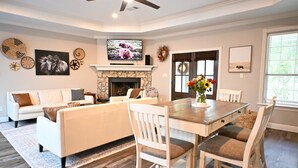 A living room with a fireplace, white furniture, and a television. - Modern Farmhouse in Wallisville! (Wallisville)