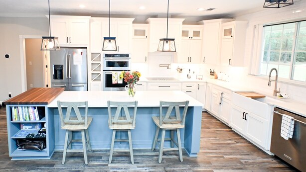 A modern kitchen with white cabinetry, a large island with bar stools, stainless steel appliances, and pendant lighting. - Modern Farmhouse in Wallisville! (Wallisville)