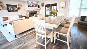 A spacious living room with a dining area, a fireplace, and a TV mounted on the wall. - Modern Farmhouse in Wallisville! (Wallisville)