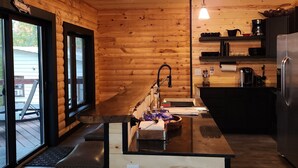 A modern kitchen with wooden walls, a central island, and a stainless steel refrigerator.