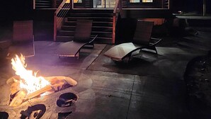 A log cabin with a porch, outdoor seating, and a fire pit.