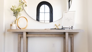 A wooden console table with a round mirror, a chandelier, and a framed inspirational quote. - Huge Private Pool. 5 King Suites. Near Sand Hollow and Zion. Sleeps 32. (Hurricane)