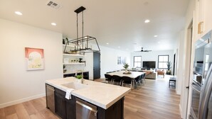 Une cuisine moderne dotée d’un îlot central, d’appareils électroménagers intégrés et d’un coin repas avec une grande table et des chaises.