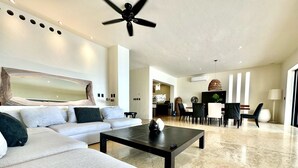 Amplia sala de estar con un sofá moderno, una mesa de centro y un comedor con sillas y una mesa.