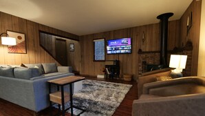 A living room with a sofa, a coffee table, a TV, a fireplace, and wooden walls. - Relax at the Cozy Cabin, just a 5-min drive to it all (Harbor Springs)
