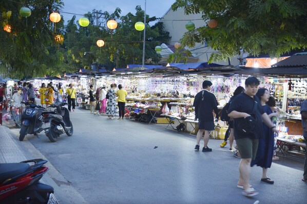 A bustling outdoor market with various stalls and people shopping.