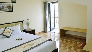 Ein Hotelzimmer mit Bett, Nachttisch, Schreibtisch und Balkon.