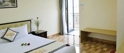 Une chambre d’hôtel avec un lit, une table de chevet, un bureau et un balcon.