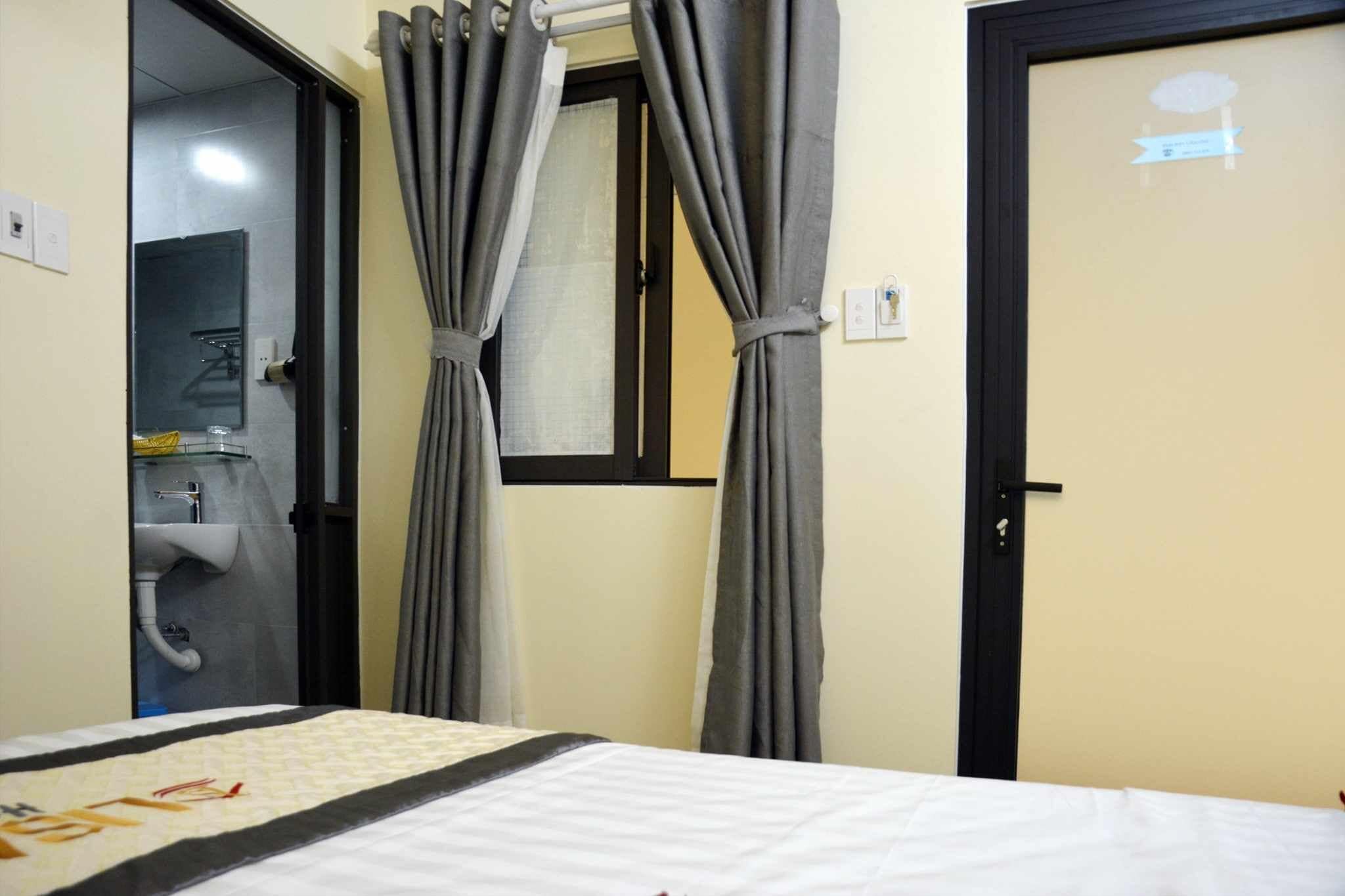 Ein Hotelzimmer mit Bett, Badezimmer mit Waschbecken und Spiegel sowie zwei Türen.