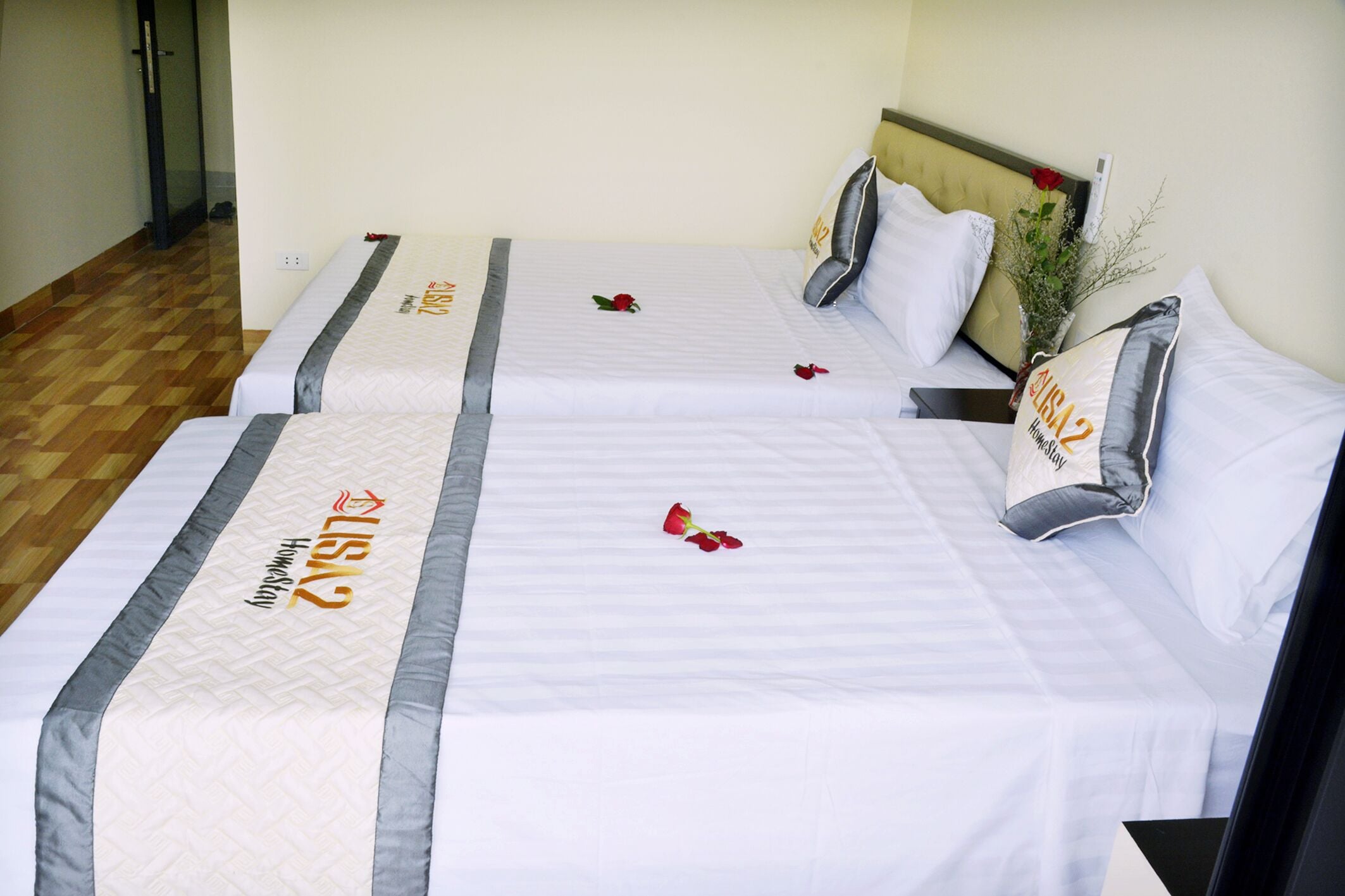 Two twin beds with matching headboards, a bedside table, and a vase with a single red rose.