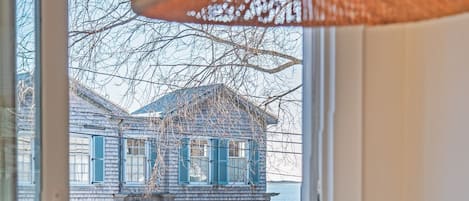 A view from a window overlooking a wooden deck and a house with blue shutters.