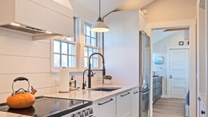 Une cuisine moderne avec des meubles blancs, une cuisinière en acier inoxydable et une poutre en bois au plafond.