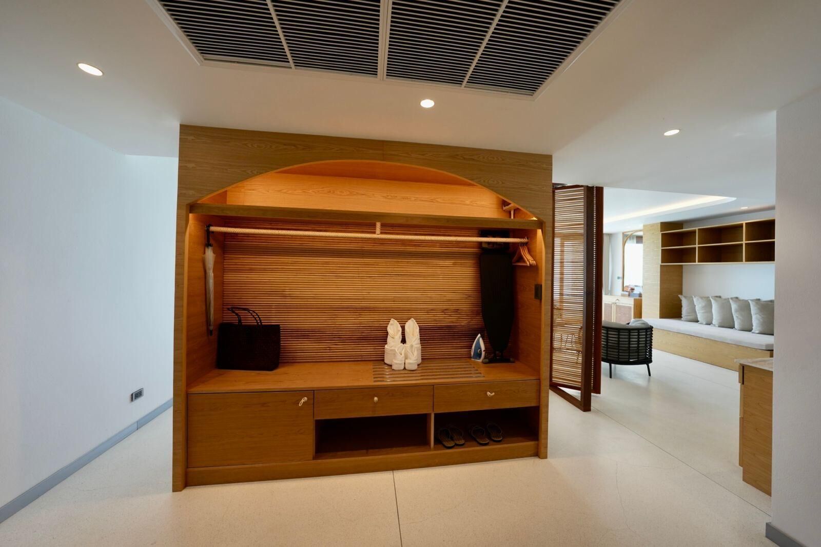 A modern interior with a wooden bench, storage compartments, and a seating area with cushions.