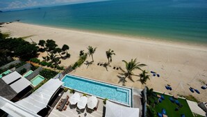 A beach view with a swimming pool, palm trees, and lounge chairs. - Elite Atoll Beachfront Hotel (Khanom)
