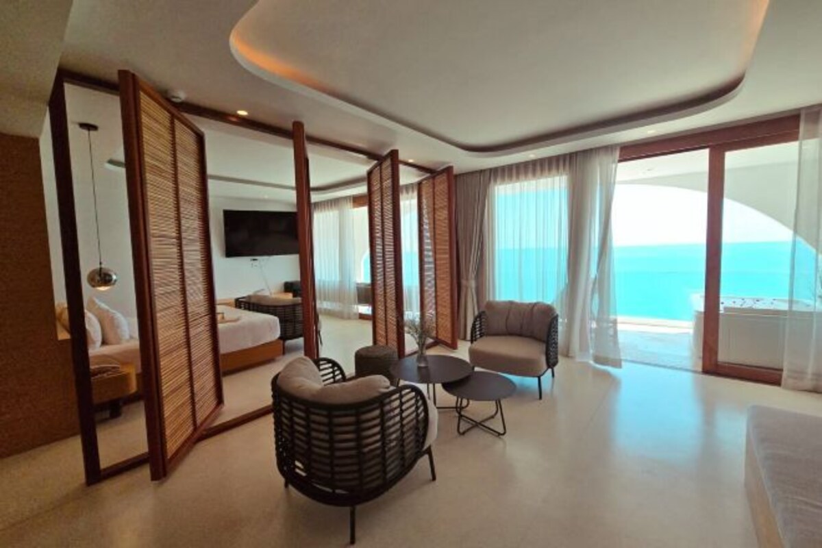 Una habitación de hotel moderna con balcón, cama, sofá y televisor.