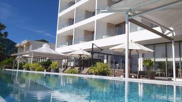 Un hotel moderno con zona de piscina, mobiliario exterior y vistas del paisaje circundante.