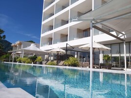 Un hotel moderno con zona de piscina, mobiliario exterior y vistas del paisaje circundante.