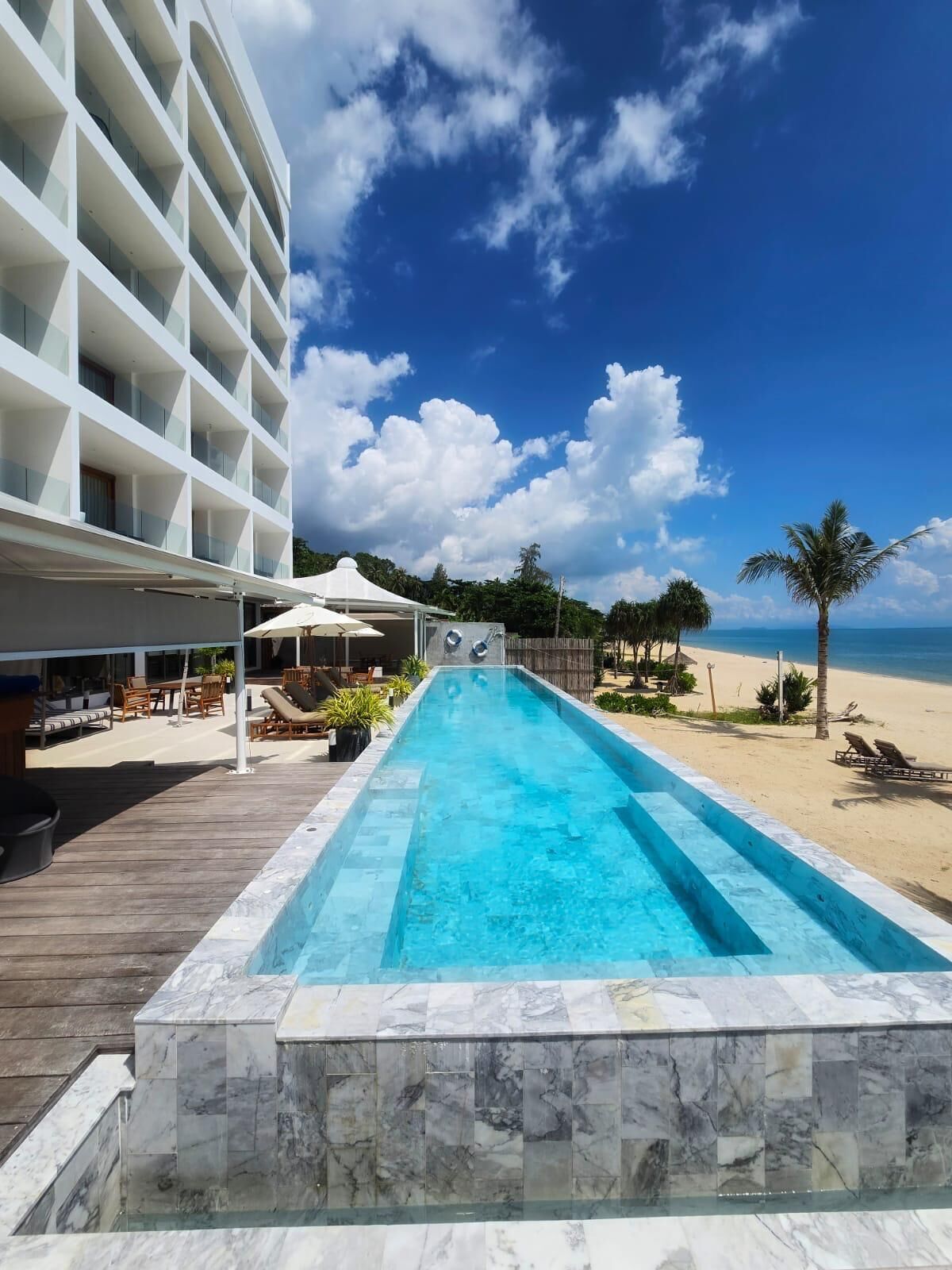 Une piscine avec vue sur la plage et un bâtiment d'hôtel en arrière-plan.