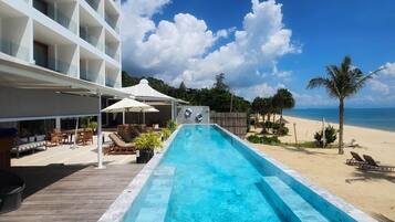 Une piscine avec vue sur la plage et un bâtiment d'hôtel en arrière-plan.