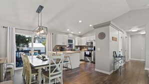 A modern kitchen with white cabinets, a central island, and a dining area with a wooden table and chairs.