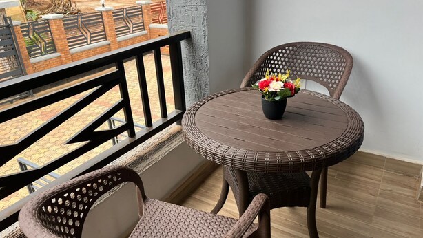En balkon med fletmøbler, et rundt bord og en blomstervase.
